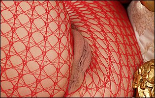 Jane Darling in red body fishnet posing and playing with a dildo