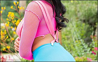 Jenna Foxx in pink fishnet top and blue pantyhose posing outdoor