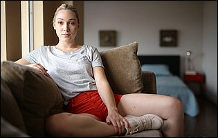 Beautiful blonde Lily LaBeau in t-shirt and sneakers strips for camera